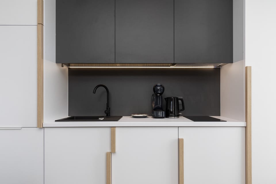 A sleek kitchen design with black and white cabinetry, featuring a compact yet functional layout.
