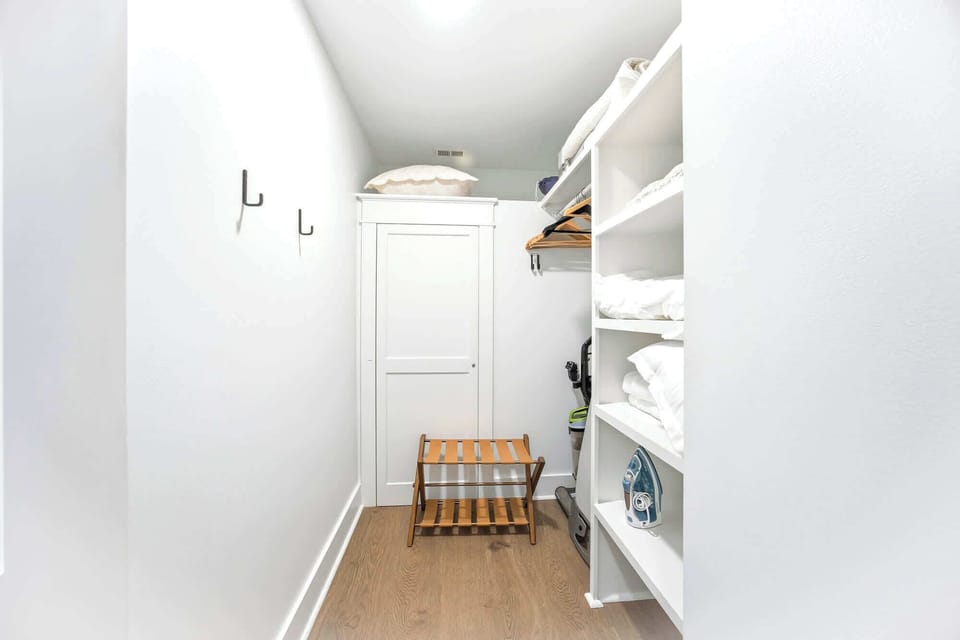 Organized shelves and a leather luggage rack offer a tidy spot to unpack, while bright walls create a clean, airy feel for your belongings. This functional nook pairs oak-toned floors with plenty of space to keep your travel essentials ready.