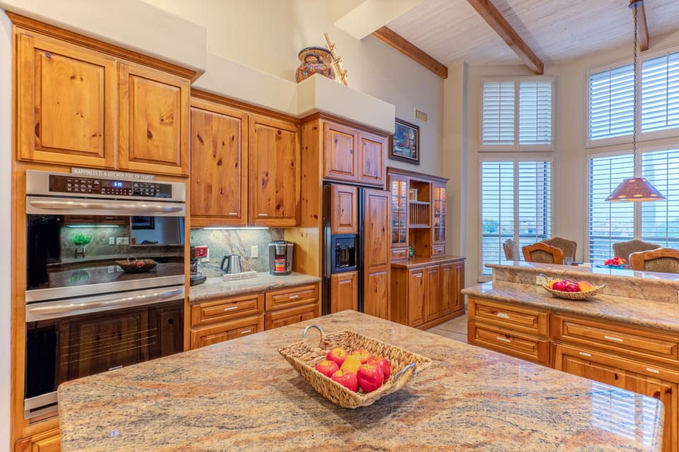 Granite island and wrap-around counters provide generous space for prepping and serving feasts.