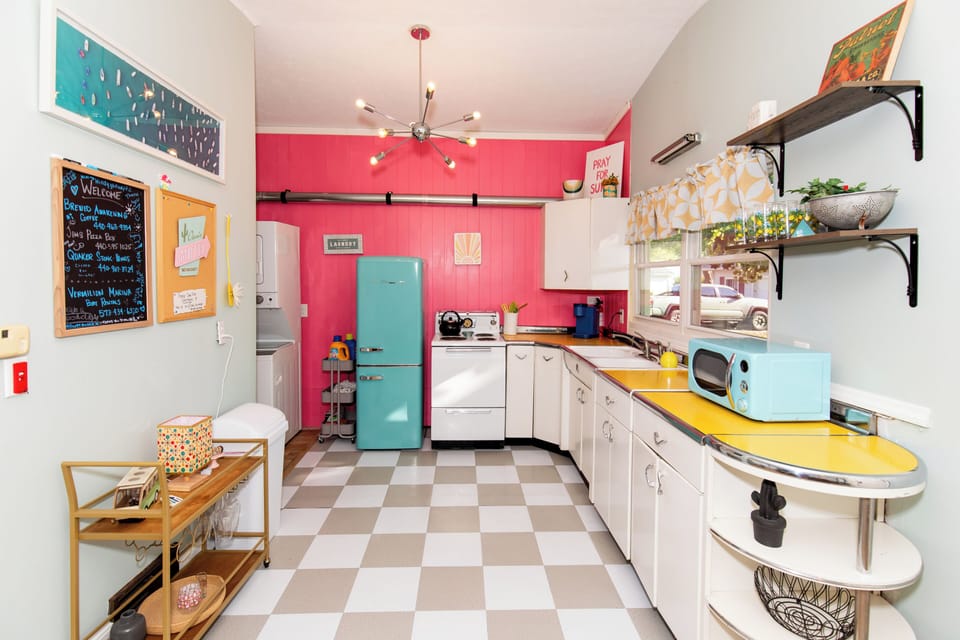 Step into your vibrant retro kitchen with cheerful coral walls, vintage turquoise appliances, and sunny yellow countertops that make cooking a joyful experience.