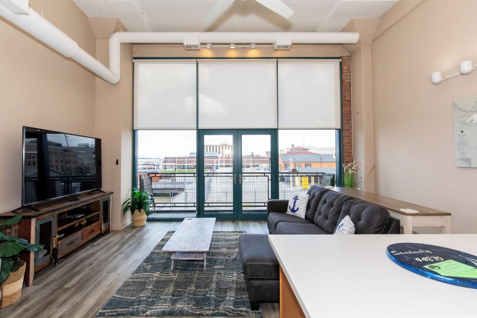 Relax in your stylish loft with exposed beams, lake views, and modern comforts including large TV and cozy seating.