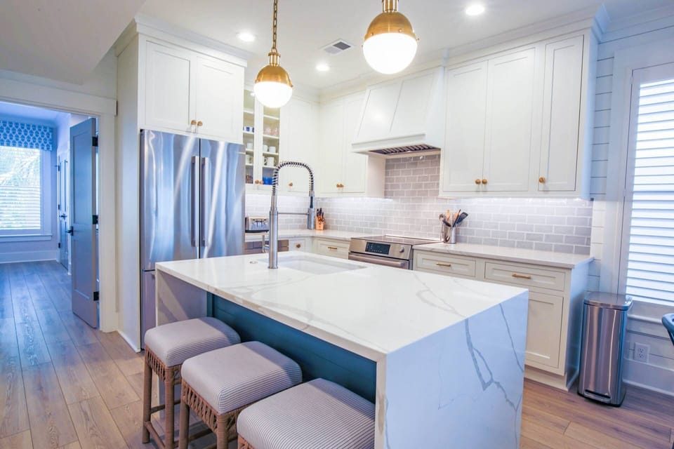 The kitchen centers around the island with waterfall counters, pendant lighting and a sink.
