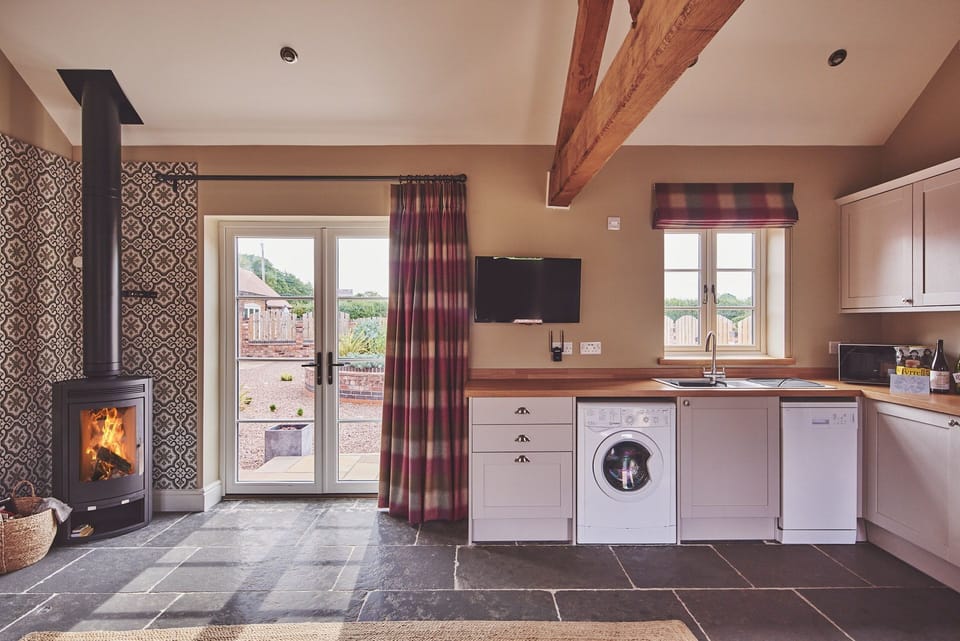 The wood-burning stove and kitchen at Stable Cottage, Worcestershire