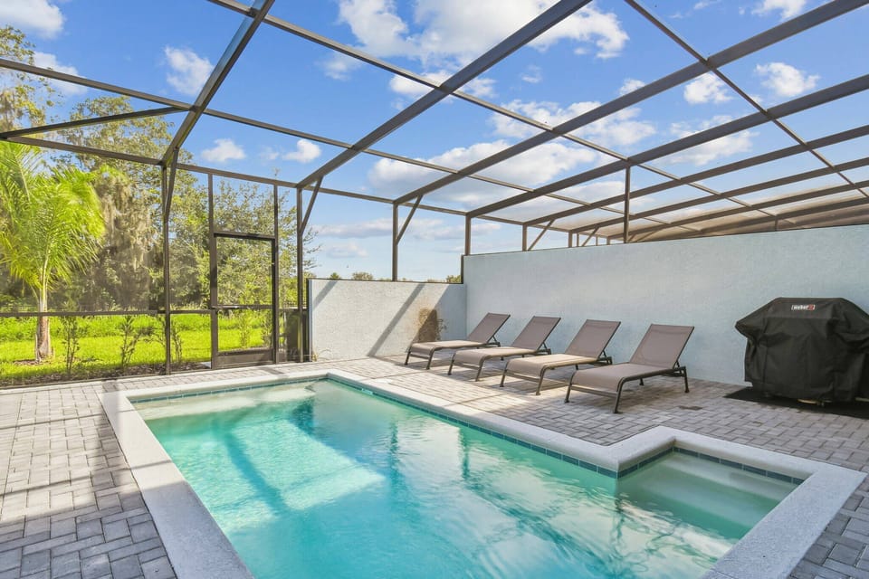 Step outside to a private oasis featuring a sparkling pool surrounded by sleek lounge chairs, perfect for sunbathing. The spacious screened enclosure ensures a relaxed atmosphere while you enjoy the lush green views and fresh air.