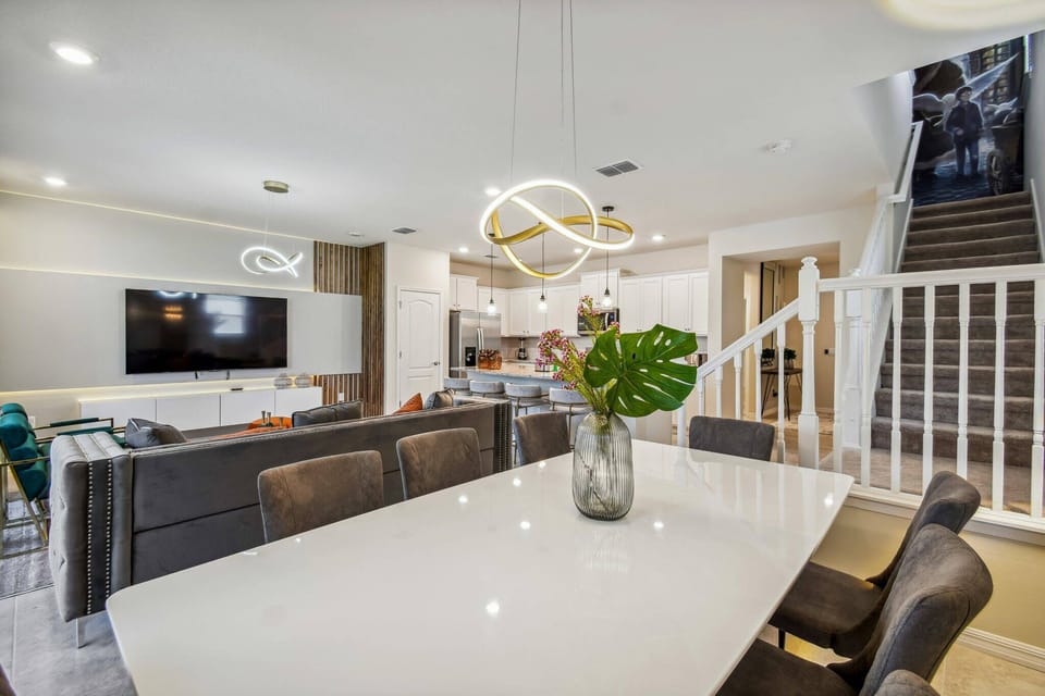 Enjoy a cozy dining area with a stylish white table and comfortable dark seating, all under a modern light fixture. The open layout seamlessly connects to the kitchen and living room, making it an ideal spot for gatherings.