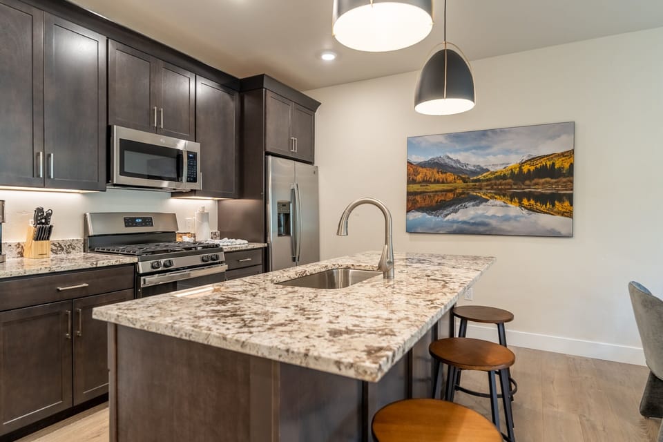 Your fully equipped kitchen features granite countertops, stainless appliances, and stylish pendant lighting—perfect for preparing meals together.
