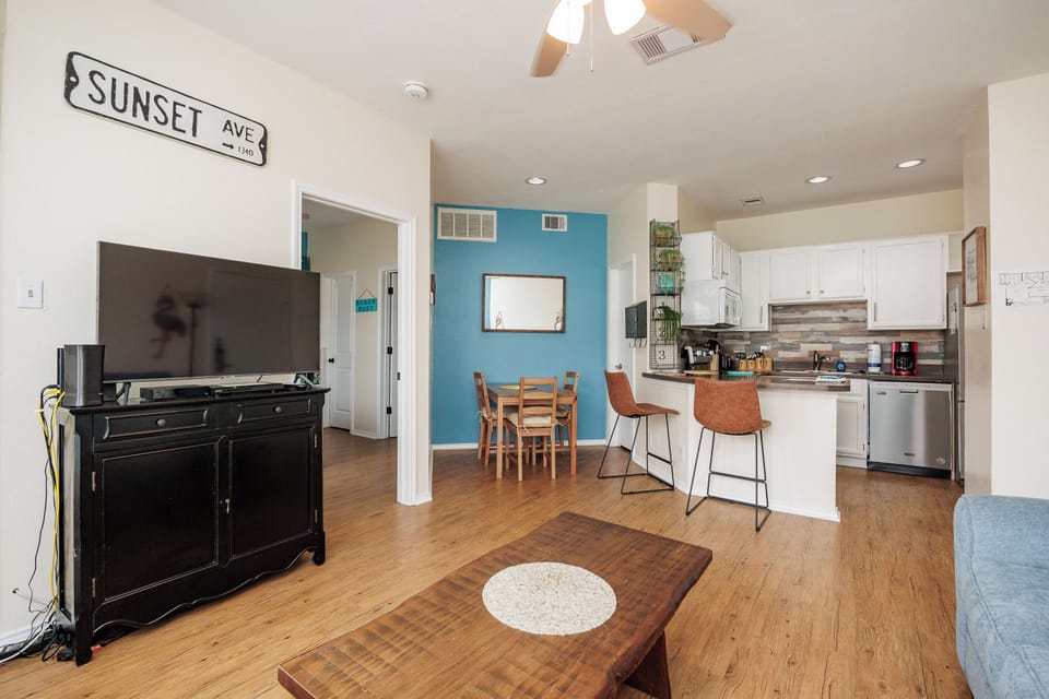 Unwind in your bright open-plan space where coastal vibes meet modern comfort, featuring a fully equipped kitchen and cozy seating.