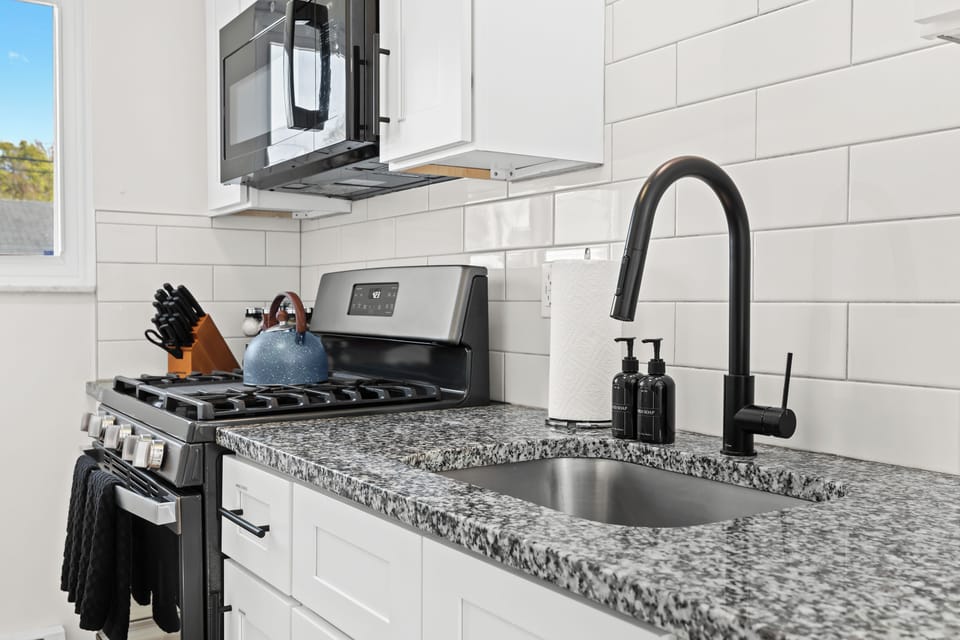 Stylish kitchen with granite countertops, a matte black faucet, and stainless steel appliances — perfect for cooking in comfort and style.