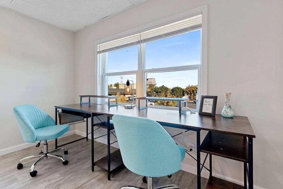 Spacious living room area overlooking downtown De Pere with a formal dining table and double desk workspace.