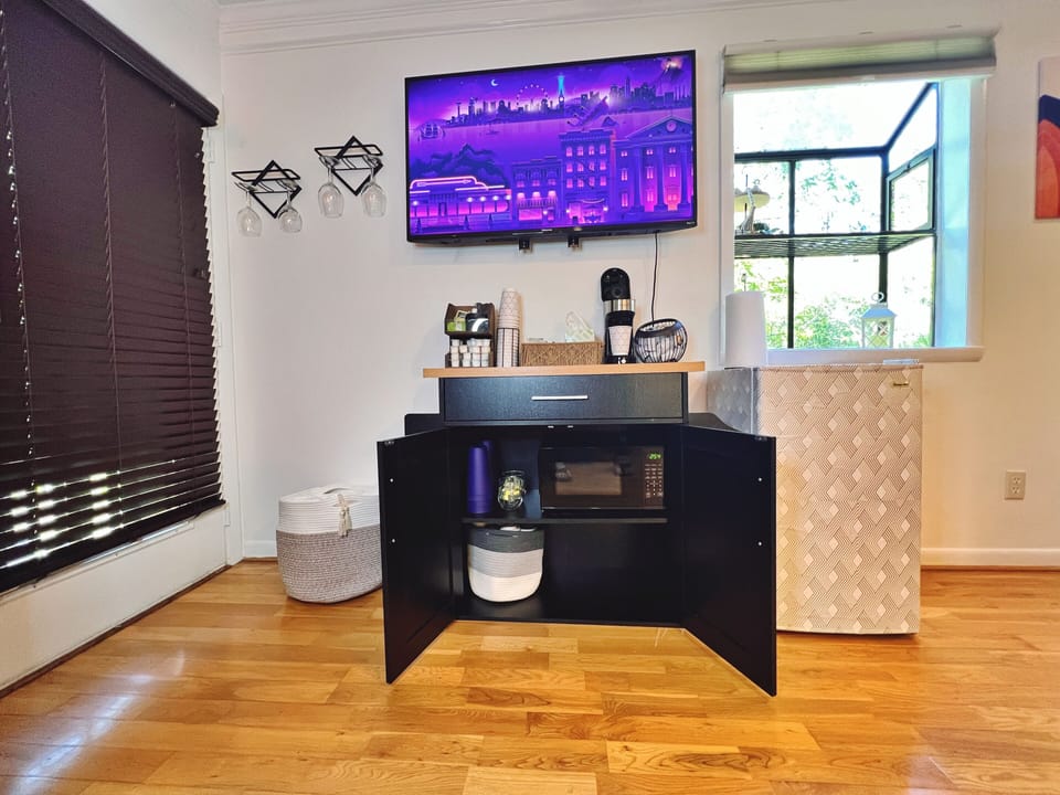 Inside coffee bar: microwave, dishes, plastic cups and dish towel and silverware