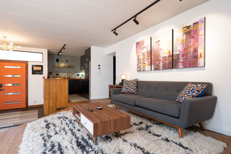 Unwind in your modern living space with sleek furniture, vibrant artwork, and cozy textured rug.