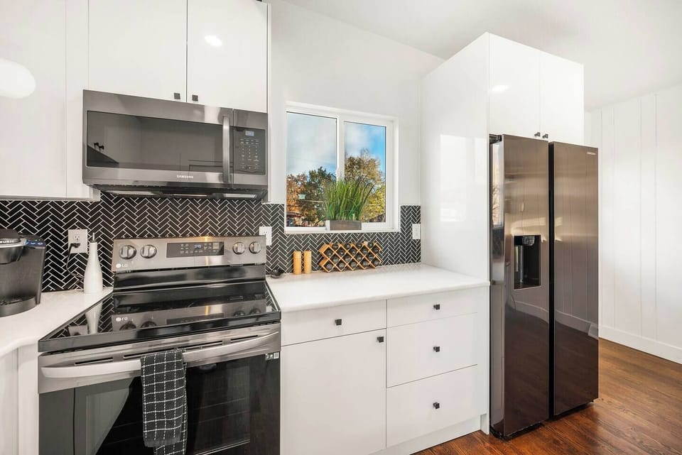 Fully stocked kitchen with stainless appliances cookware, spices and serving ware.