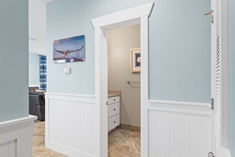 Soft blue walls and coastal artwork create a peaceful retreat, leading to your private bedroom space with thoughtful details throughout.