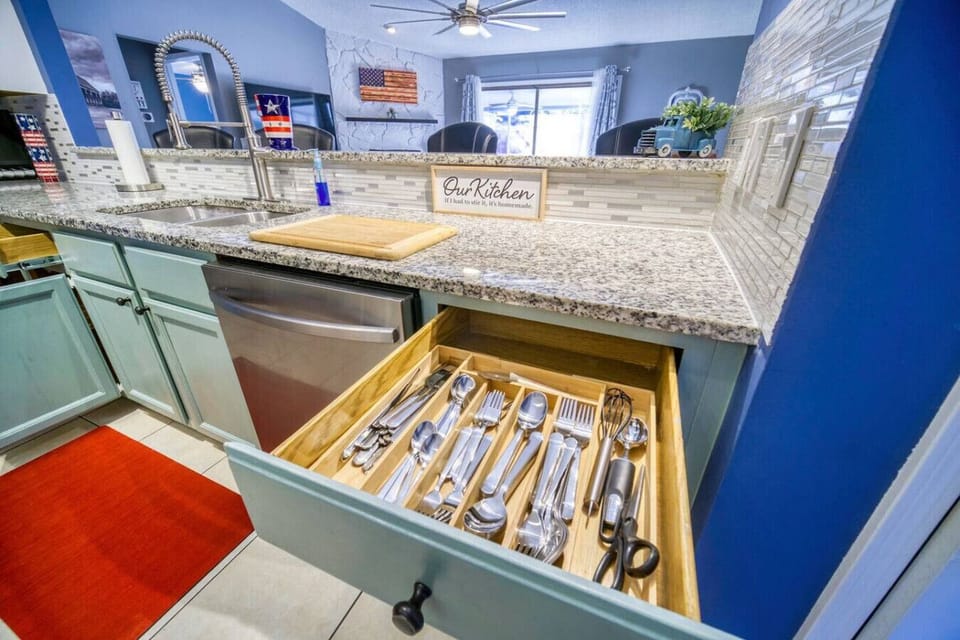 Well-organized kitchen featuring stylish granite countertops, modern appliances, and neatly arranged utensils.