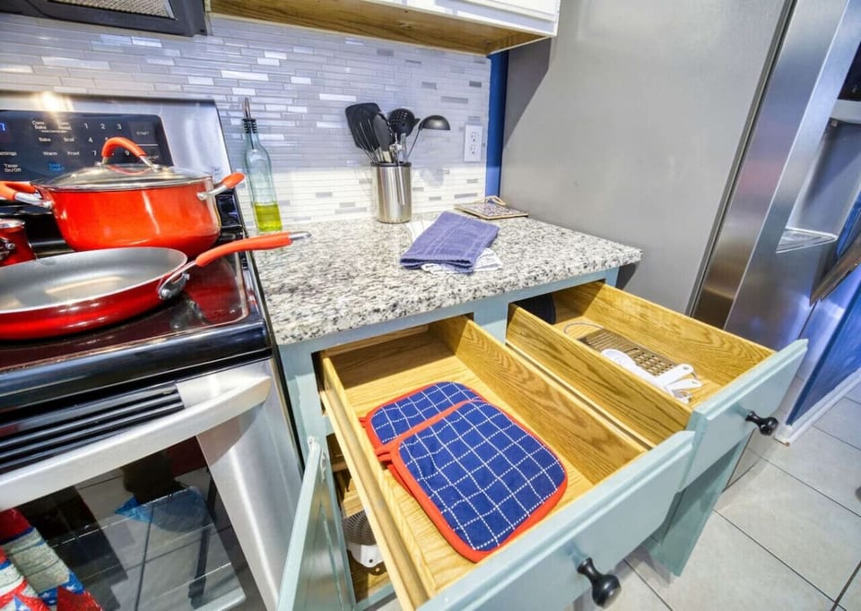 Functional kitchen with a spacious granite countertop, equipped with modern appliances and neatly organized drawers for utensils and tools.