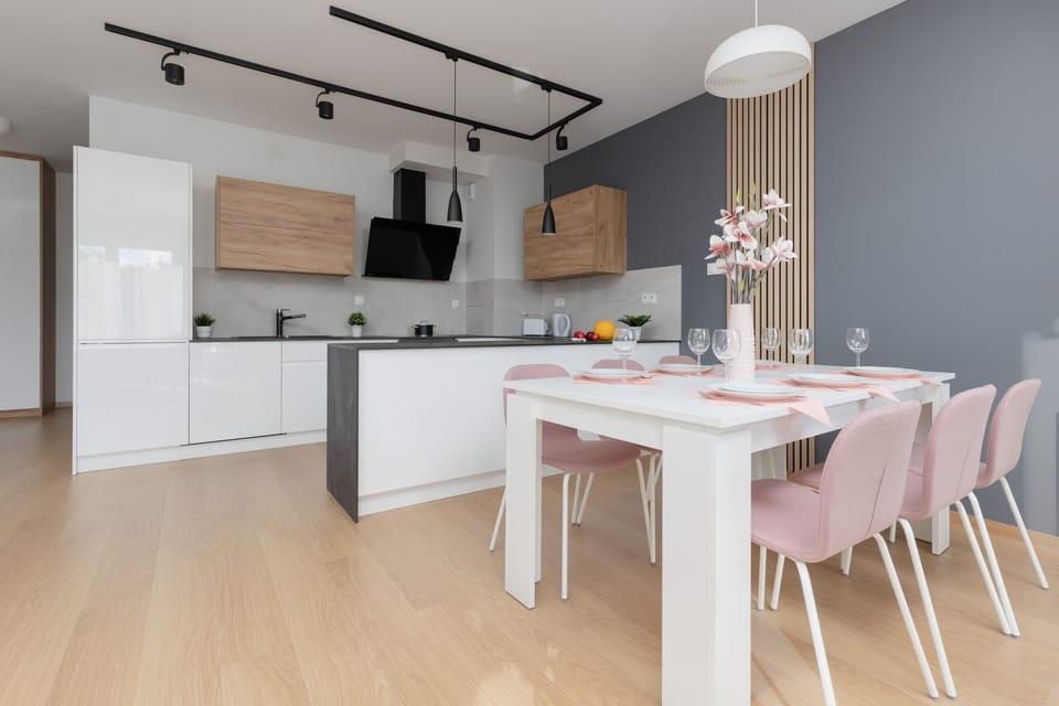 A modern open-plan kitchen and dining area with sleek white cabinets and wood accents, blending functionality with style.
