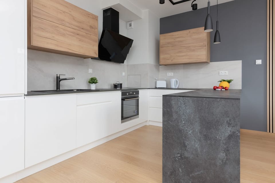 A modern open-plan kitchen and dining area with sleek white cabinets and wood accents, blending functionality with style.
