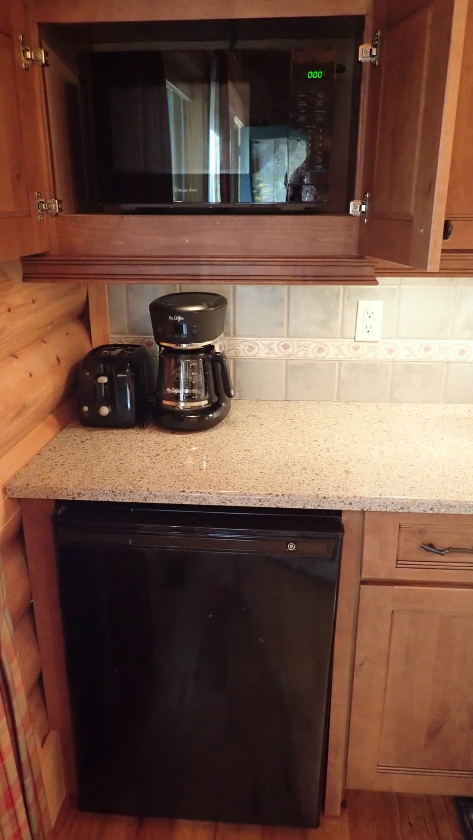 Toaster, coffee pot, refrigerator and microwave in the kitchen area.