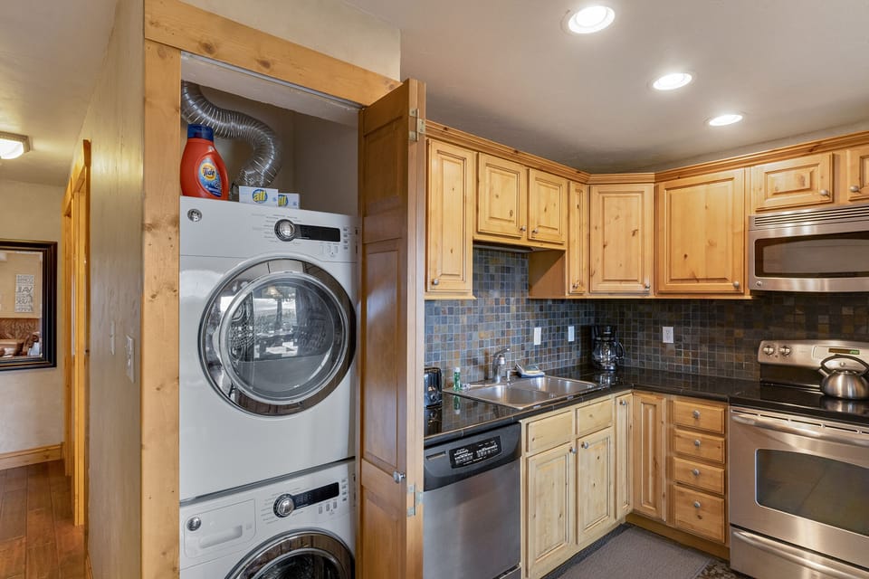 Closet next to kitchen houses a stacked washer and dryer.