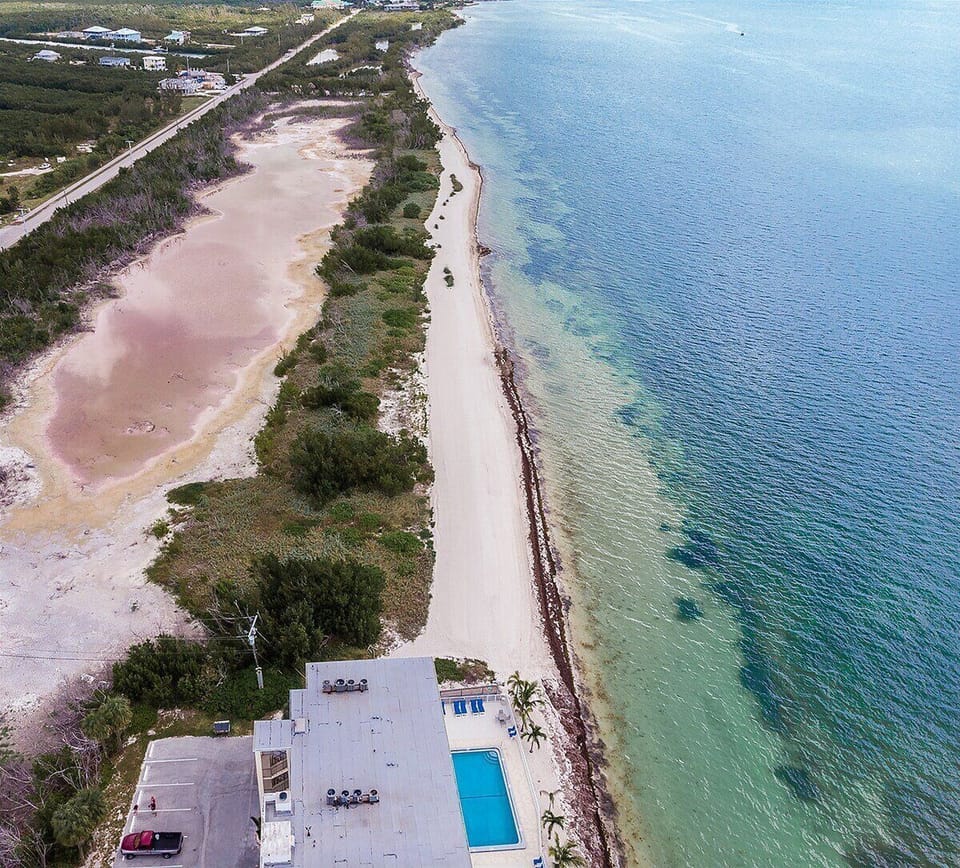 From above, the stunning coastline reveals miles of shoreline bordered by crystal-clear water on one side and protected natural beauty on the other.