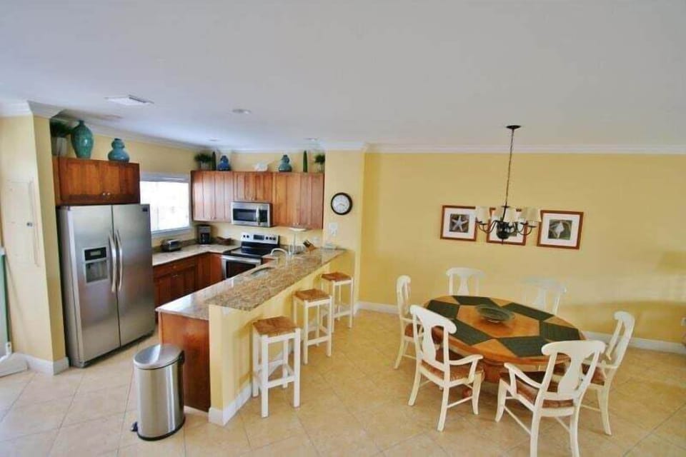 Open-concept dining area with seating for six, seamlessly integrated with a fully equipped kitchen featuring bar stools.