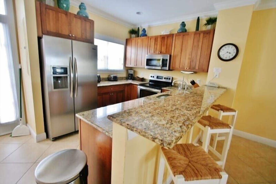 Open-concept dining area with seating for six, seamlessly integrated with a fully equipped kitchen featuring bar stools.