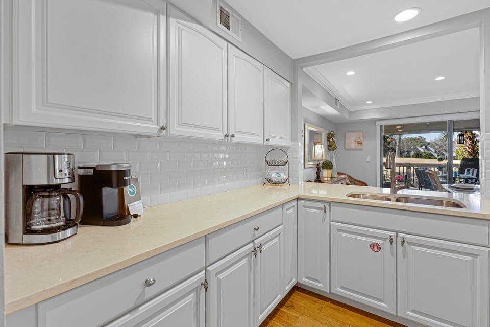 Solid surface countertops provide generous prep space, and the open pass-through keeps you connected to the dining and living areas.