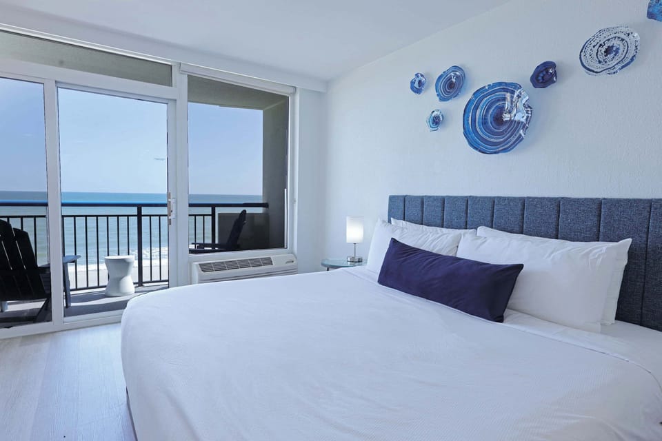 Wake up to breathtaking ocean views from your cozy bedroom retreat, featuring a plush bed, flat-screen TV, and private balcony access for the perfect blend of comfort and coastal charm.

