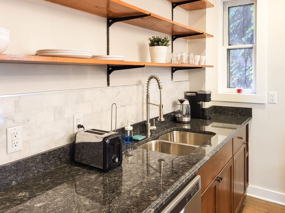 Kitchen comes equipped with large sink area, countertops and shelves for storage