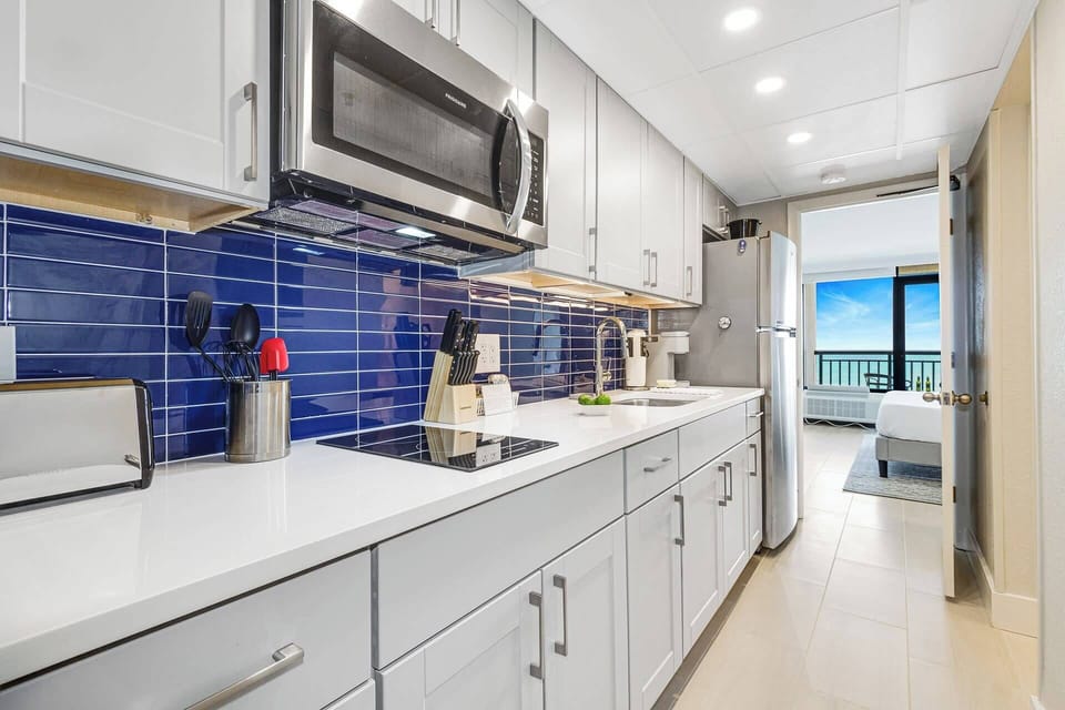Modern kitchen with stainless steel appliances, quartz countertops, and ocean views. 
