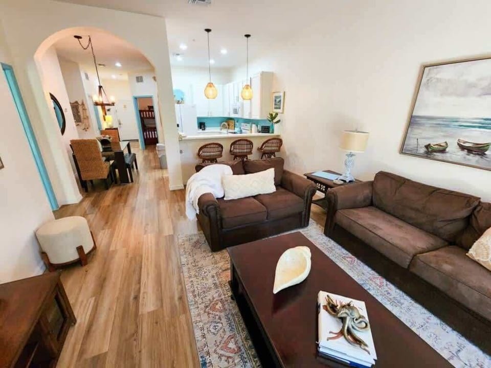 - Open living room with sofa seating coffee table and warm natural light
- Spacious lounge connects kitchen dining and relaxation areas
- Comfortable living space designed for family vacation stays  
