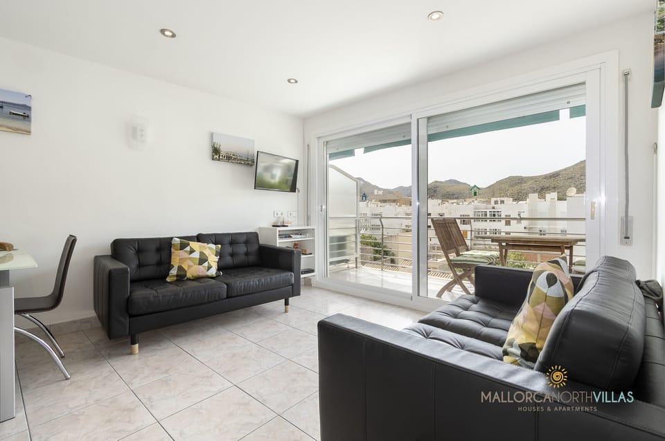 Bright living room with two sofas, dining area and balcony access with mountain views in Port de Pollença