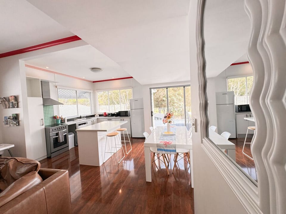 Open-Plan Living - Lounge, Kitchen & Dining with Deck Access and Park Views  Enjoy a seamless flow in our open-plan lounge, kitchen, and dining area, designed for comfort and connectivity. This spacious setting includes a cozy lounge with a 90-inch TV and