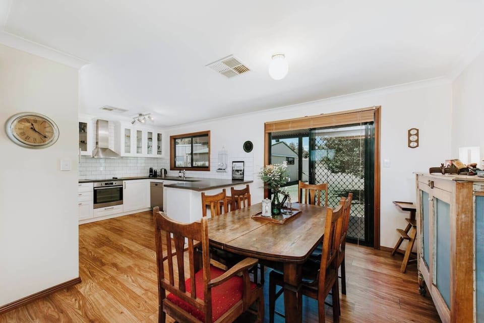 Directly across the kitchen is a dining table seating six, perfect for shared meals at home.
