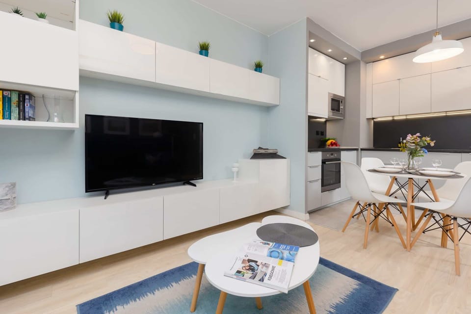 A spacious living area with a mounted TV, stylish shelving, and comfortable furnishings for relaxation.
