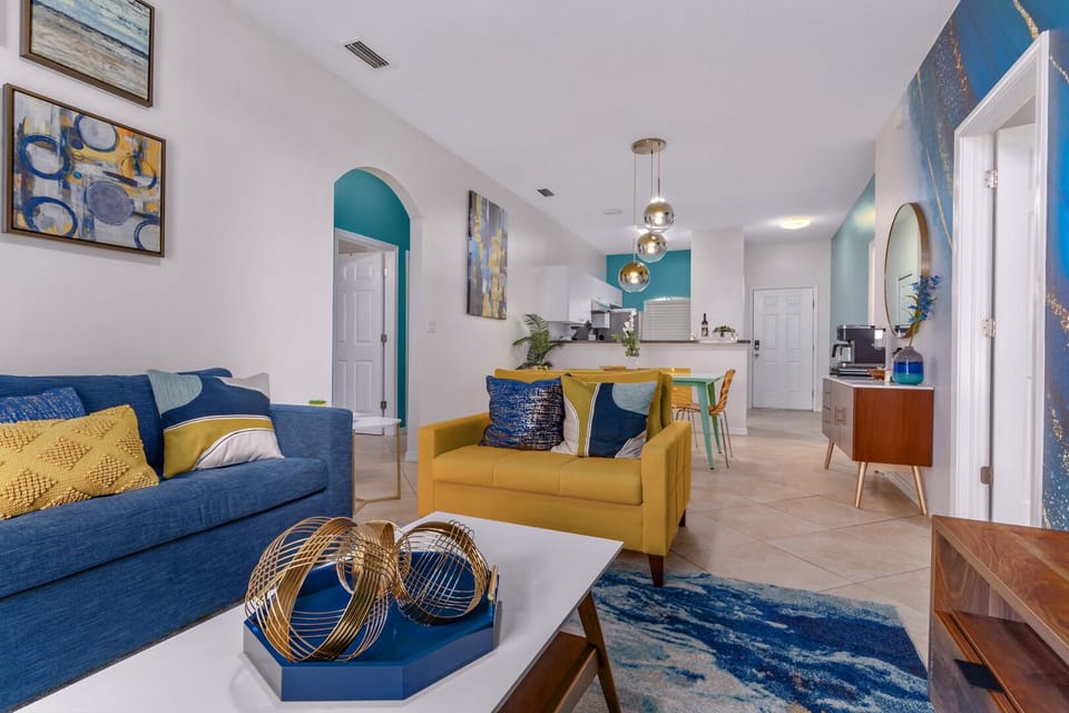 Colorful and cozy living room with attached kitchen and access to patio.