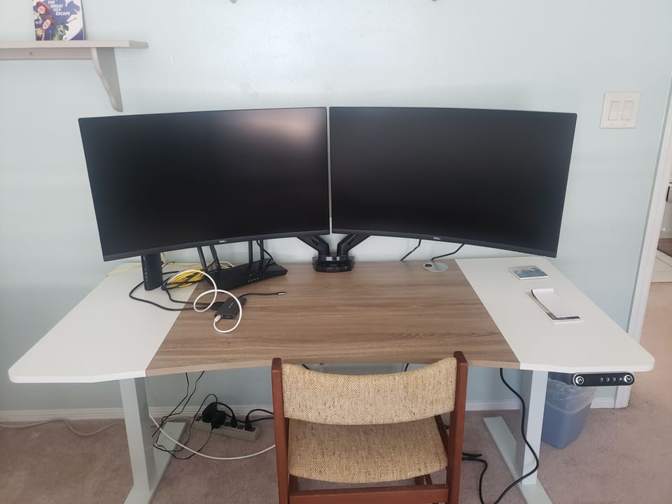 Workstation with two monitors, adjustable height desk, and docking station.