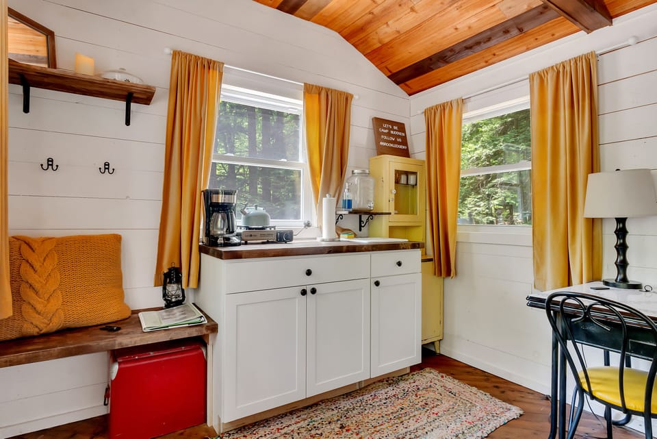 Step into an enchanting world of rustic charm and delightful details! Our adorable kitchenette, complete with a cozy bench, vintage cooler, and charming table, is a recipe for memorable moments. 