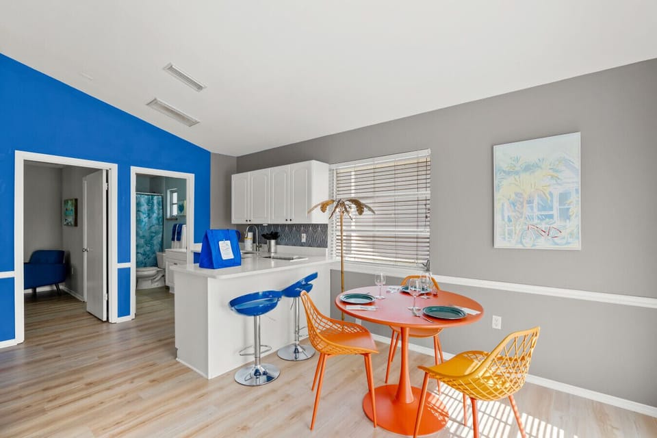 Siesta Key Beach kitchen with bold blue walls, orange dining, and peek-through views to guest spaces.
