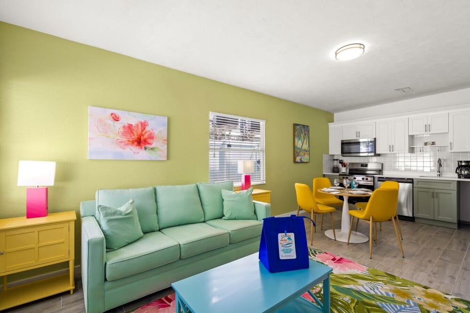 Siesta Key Beach living and dining area with pastel green couch, yellow chairs, and floral accents for cheerful coastal comfort