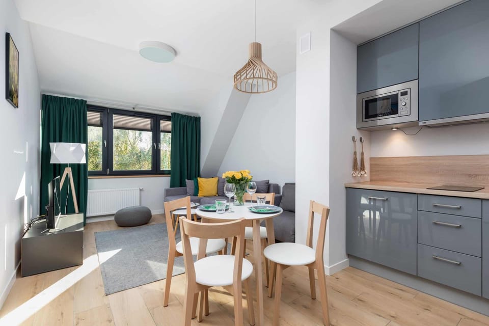 A cozy dining space with a round table set for four, adorned with vibrant green accents and natural light.