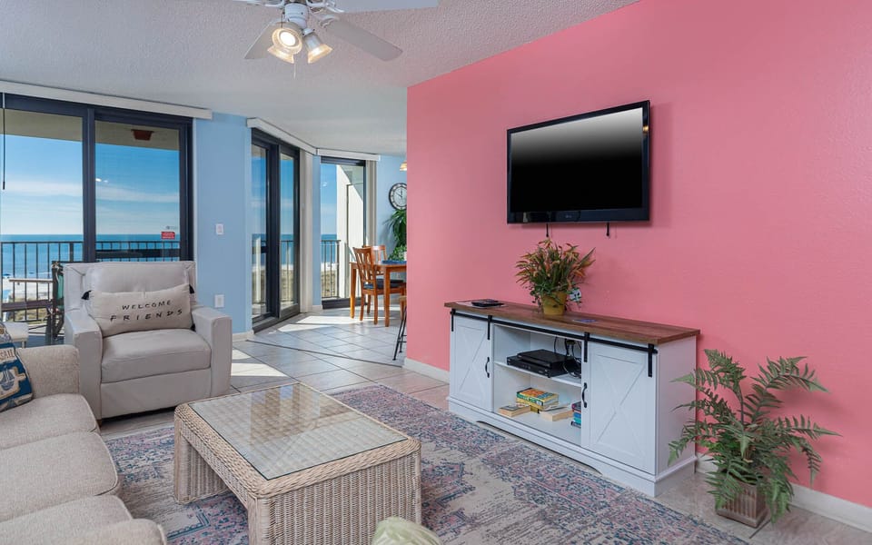 Bright living area features a comfortable sofa with queen sleeper, a TV, and a dining space with views of the gulf