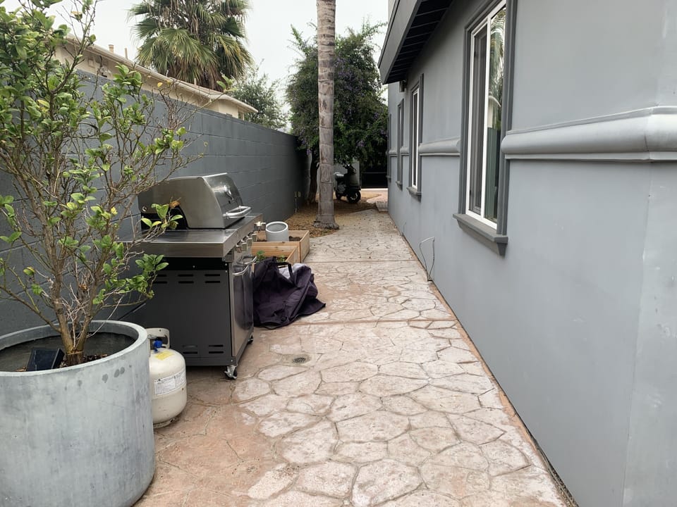 Side of house with BBQ looking to front gate from back yard