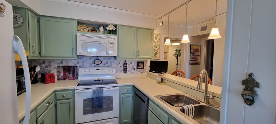 View of well lit kitchen and breakfast bar, and small TV