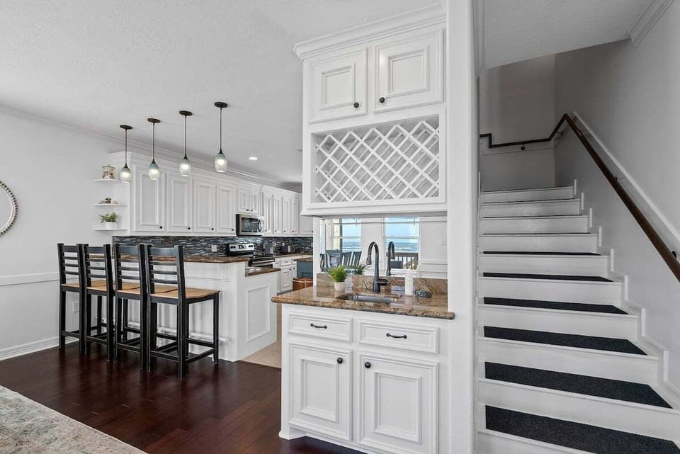 Open kitchen with granite countertops, custom cabinetry, wine storage, and breakfast bar seating for family meals and gatherings.