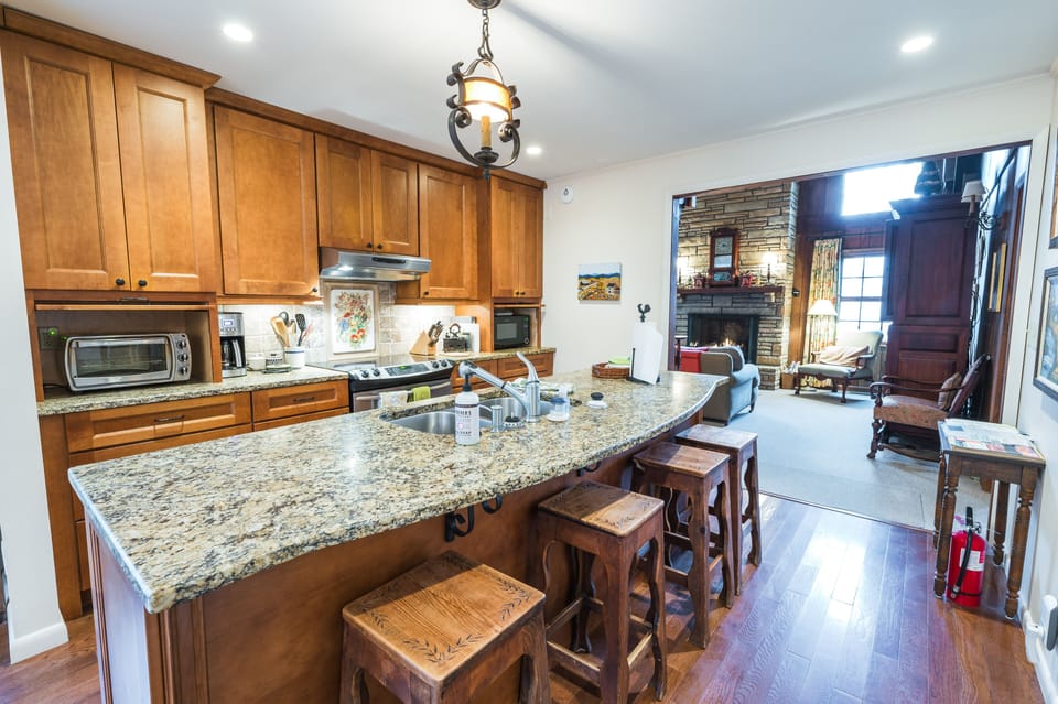 Wooden cabinets, granite countertops, and cozy living area with fireplace.