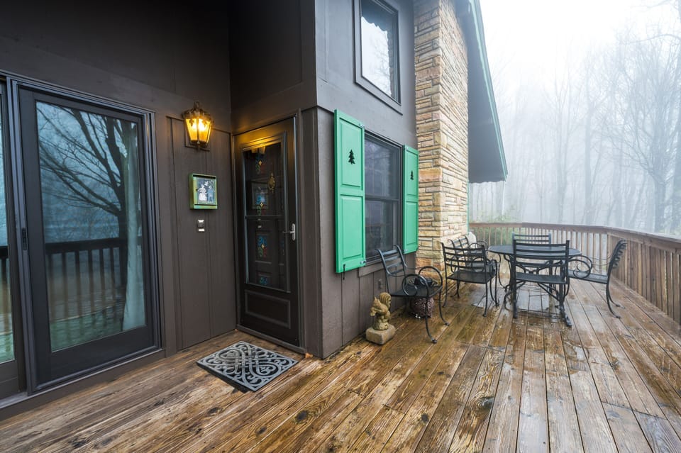 Welcoming wooden deck with seating, lantern light, and scenic misty forest view.