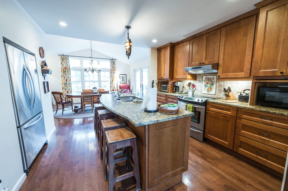 Kitchen with granite island, wooden cabinets, and dining area with large windows.