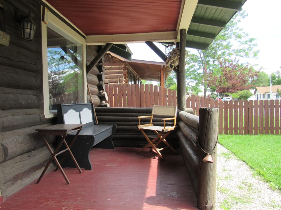 A small bench and chair with a side table in the fenced-in front yard.