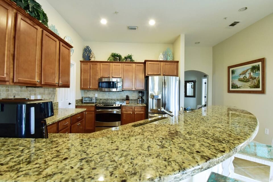 View of the fully equipped kitchen from the dining area. Walk-in pantry on the left, doorway on the right leads to the front entry, offering everything you need for a comfortable stay.